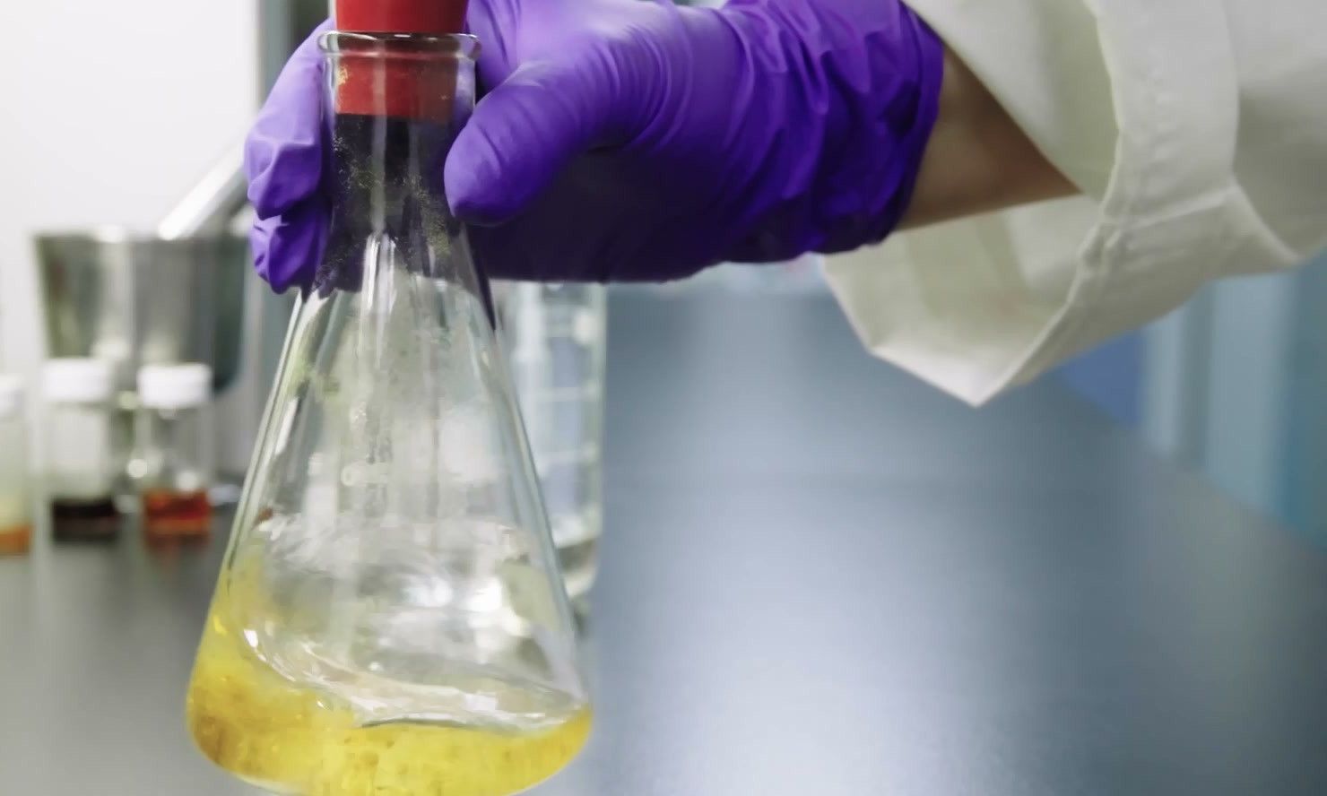 Gloved hand holding a glass flask in the lab